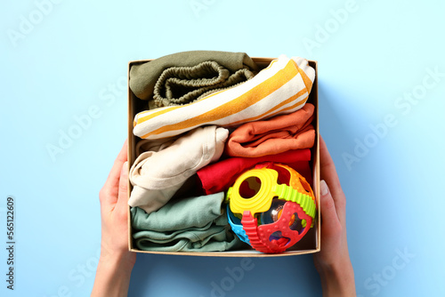 Clothing donation box with child clothes and toy in female hands. Charity concept. photo