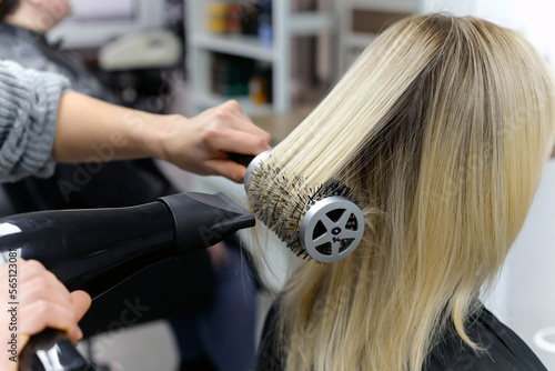 hairdresser dries hair with a hairdryer to a woman after a haircut in the salon