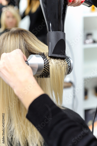 hairdresser dries hair with a hairdryer to a woman after a haircut in the salon