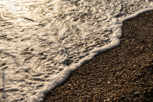 Fototapeta Naklejka Na Ścianę i Meble -  Waves splashing sand beach of Brac island, Croatia during beautiful summer sunset creating white foam