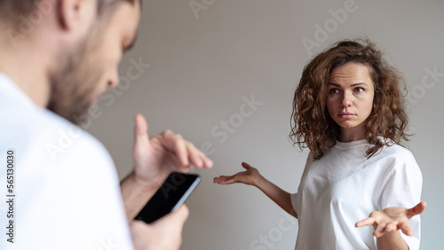 Wallpaper Mural Upset curly woman looks at husband who using mobile phone and covering screen with hand, family relationship problems.  Infidelity concept, suspicious, betrayal concept. Torontodigital.ca