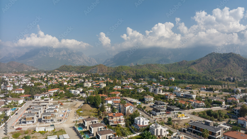 Top view of the big city. Residential houses. Urbanization. Green mountains and clouds in the background. Photography. High quality photo
