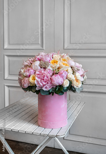 a bouquet of flowers in a pink round box of hydrangea, ozothamnus, peony, spray rose, peony rose, eustoma