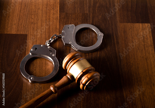 Gavel and handcuffs on wooden background