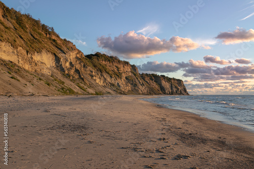 Landscape of the Baltic Sea coast in northern Europe. High steep cliff, sandy beach. Warm autumn day, yellow colors of golden autumn.