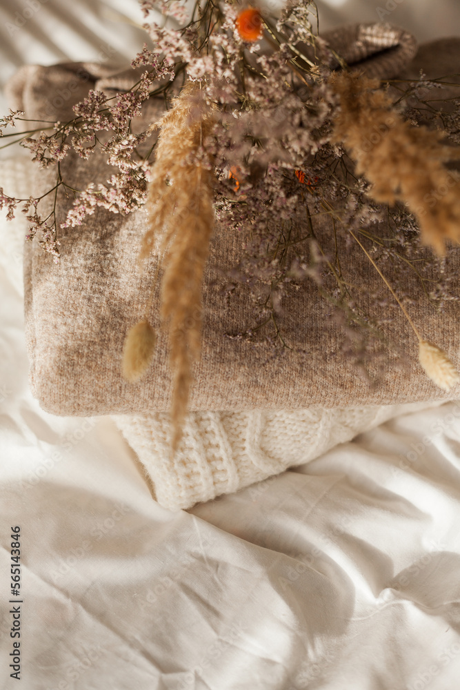 Cozy home decor. Warm winter clothes. Bouquet of dried flowers. Women things. Pastel colors.