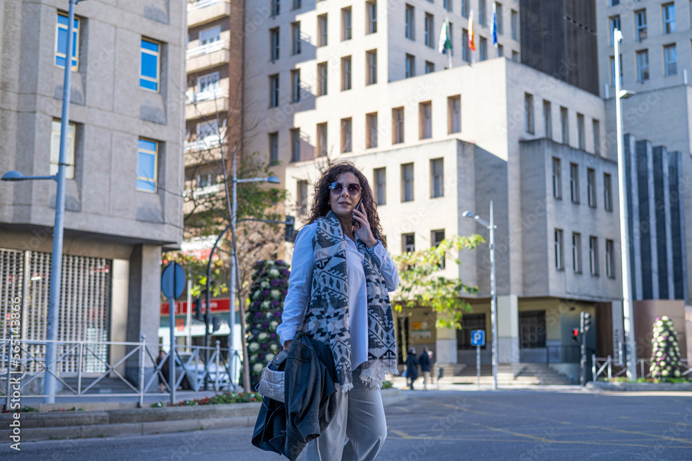 Elegant Businesswoman On Phone Conversation While Walking In Financial Area In A Sunny Day