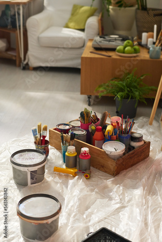 Group of paints, paintbrushes and other supplies necessary for art on the floor of home studio of modern self employed artist