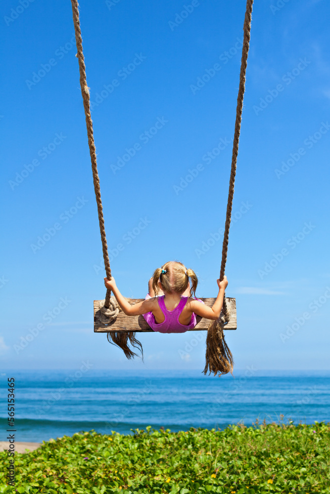 Happy girl have fun swinging high on sea beach