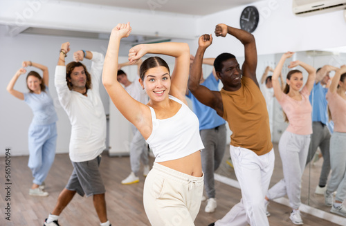 Group of energetic different people learning dance at dance class