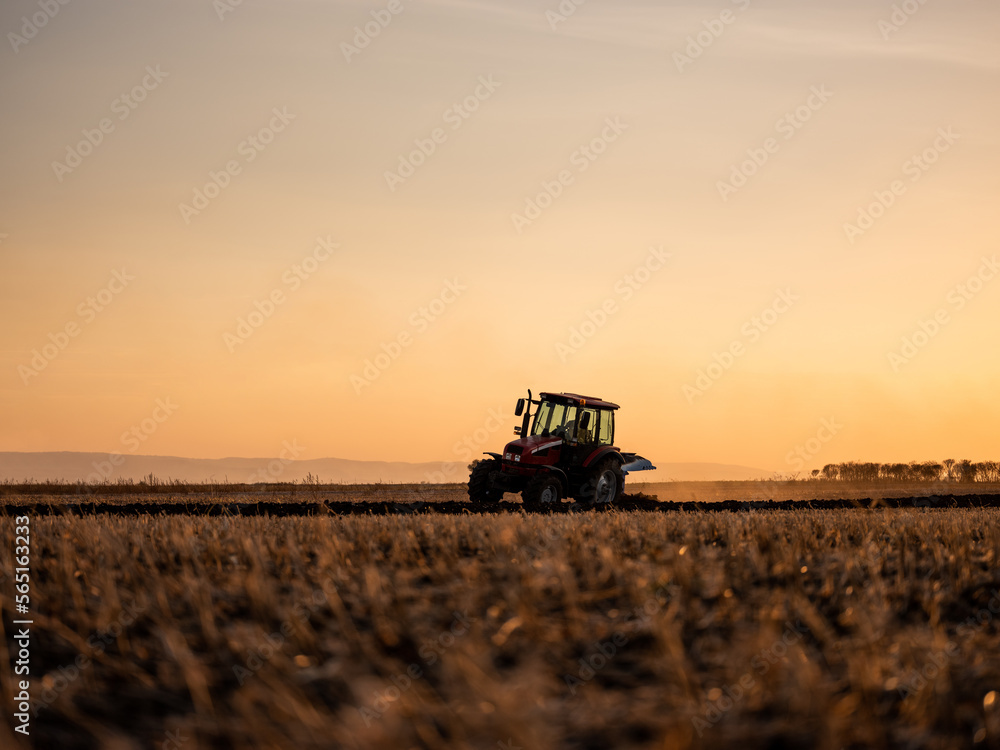 Fototapeta premium Tractor plowing and preparing stubble field for crop cultivation