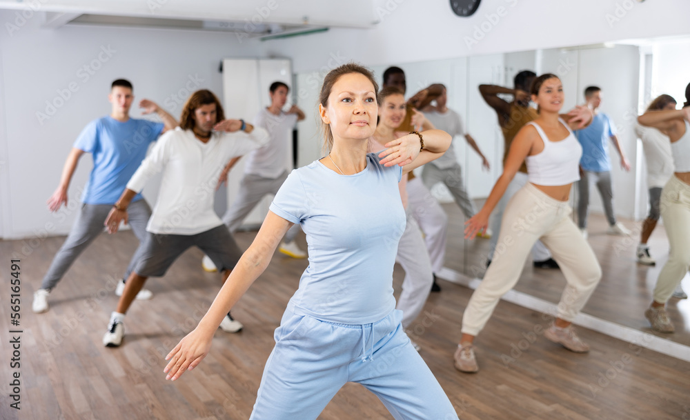 Group of active women and men practicing energetic dance in a modern dance studio