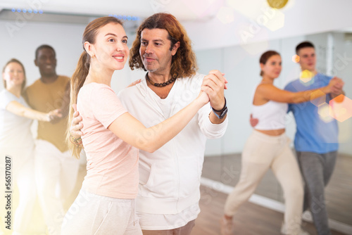 Woman and man practicing social dance moves in pair during group class