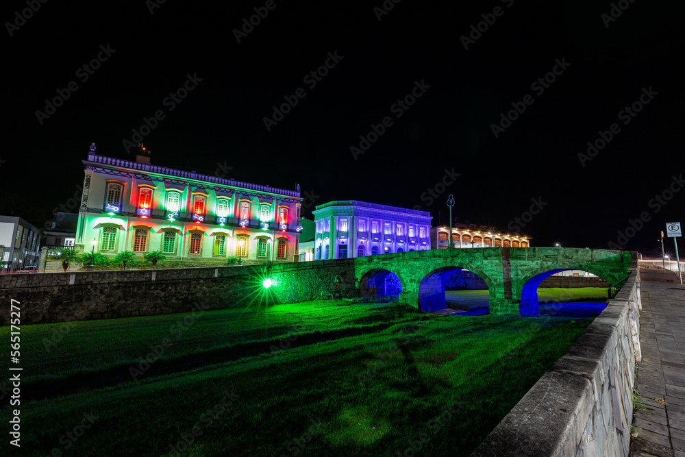 Fototapeta premium Sao Joao del Rei, Minas Gerais, Brazil. Bridge over river and old buildings of the city hall of the historic city at night