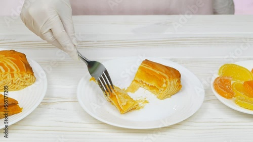 Cottage cheese casserole with pumpkin in a white plate on a white wooden table. Striped casserole with cheese and pumpkin. Chef cuts and taste the cheese pumpkin cake.