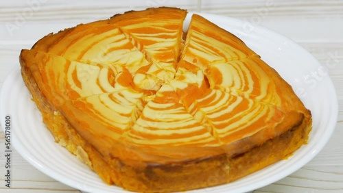 Cottage cheese casserole with pumpkin in a white plate on a white wooden table. Striped casserole with cheese and pumpkin. Cheese pumpkin cake. Cheesecake.