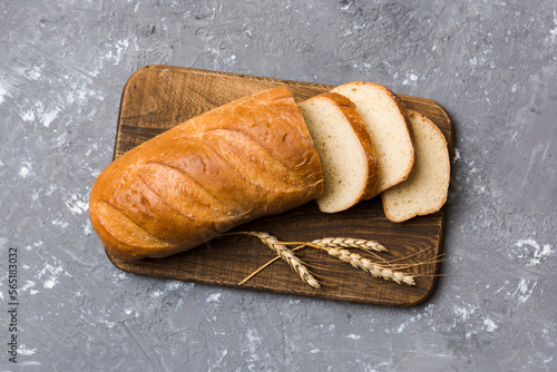 Freshly baked bread slices on cutting board against white wooden background. top view Sliced bread