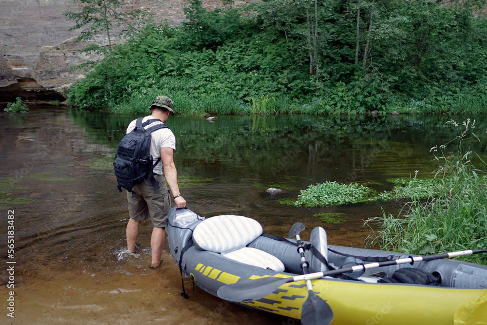 A muscular Man traveler with a panama hat and a briefcase pulls a boat into the river. A muscular Man traveler with a panama hat and a briefcase pulls a boat into the river.