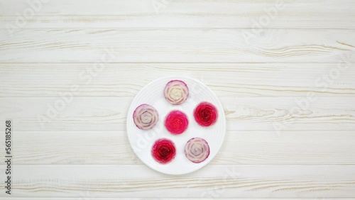 Rose shaped jelly dessert made from raspberries and cream in a white plate on a white wooden table. The chef puts a plate of dessert on the table.