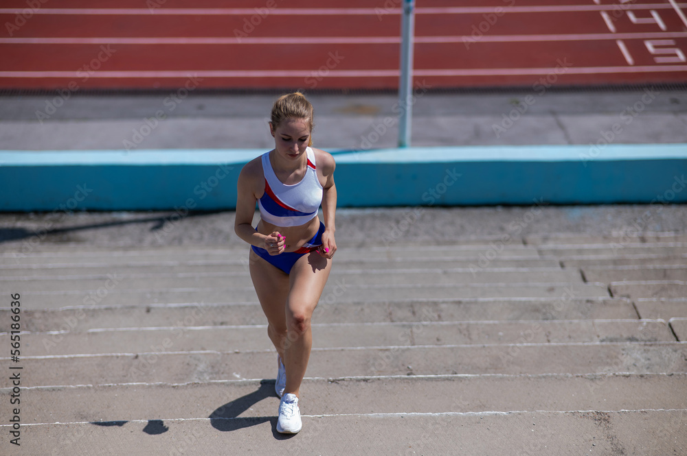Young caucasian woman running on stadium stairs outdoors. 