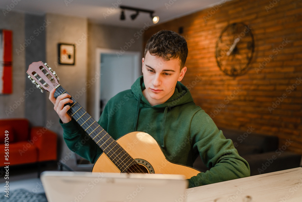 Obraz premium One man teenager learn to play guitar at home online lesson tutorial