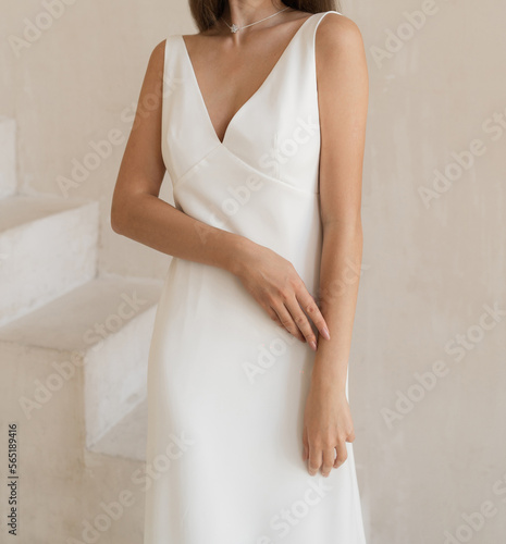 Front view of beautiful bride dressed in a white wedding dress with deep neckline. Classic wedding sleeveless dress.