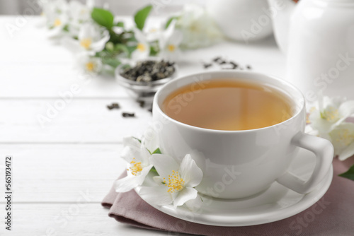 Cup of tea and fresh jasmine flowers on white wooden table