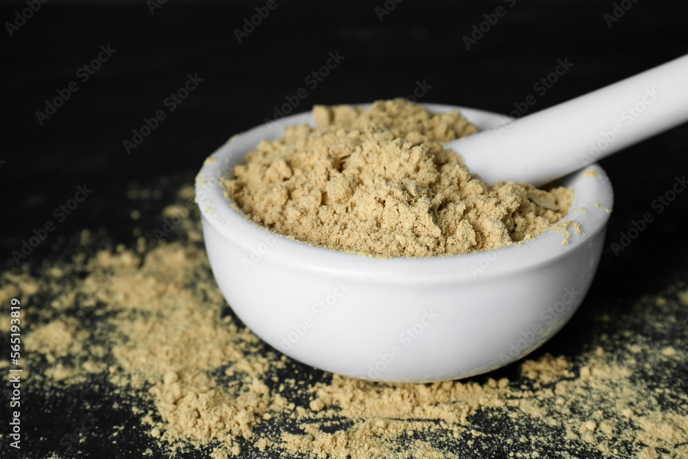 Mortar with mustard powder on black table, closeup Mortar with mustard powder on black table, closeup