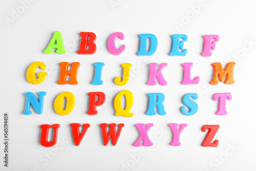 Colorful magnetic letters on white background, flat lay. Alphabetical order