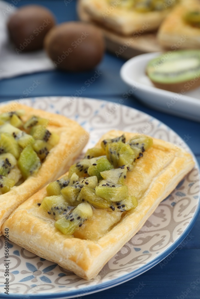 Fresh tasty puff pastry with kiwi on blue wooden table, closeup