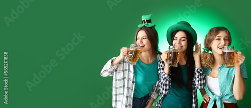 Young women drinking beer on green background with space for text. St. Patrick's Day celebration