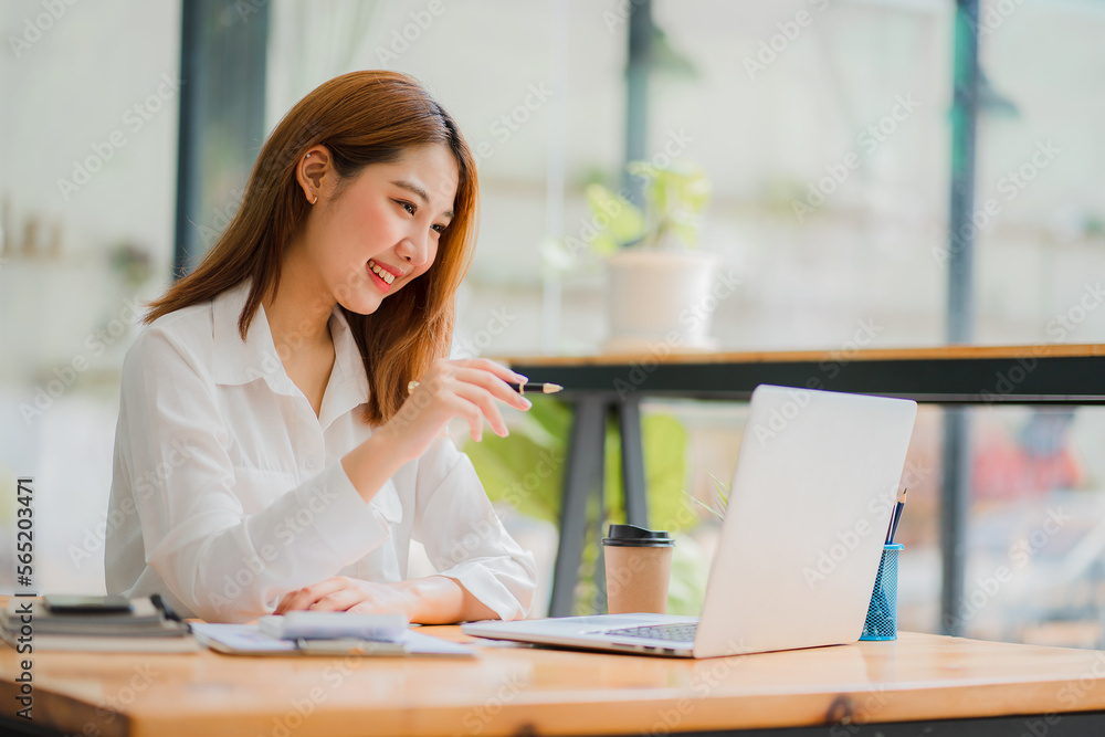 Obraz premium Pretty smiling asian female accountant working on laptop computer in modern office Accounting analysis report, finance and tax system concept