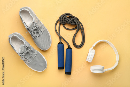 Skipping rope with headphones and sneakers on yellow background