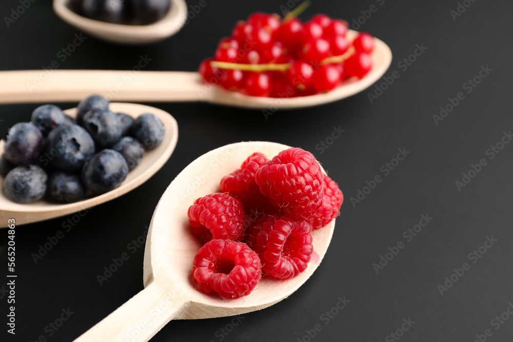 Wooden spoons with fresh berries on dark background, closeup Wooden spoons with fresh berries on dark background, closeup