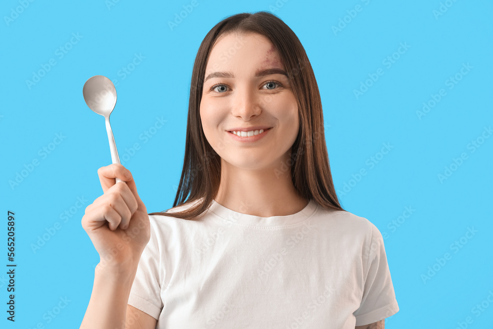 Young woman with silver spoon on blue background, closeup Young woman with silver spoon on blue background, closeup