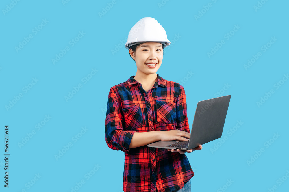 Young female engineer wearing helmet and use laptop computer