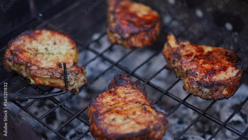 Close-up turning delicious steaks on grill outdoors in slow motion. Unrecognizable person cooking tasty meat in park on backyard. Food and picnic concept Close-up turning delicious steaks on grill outdoors in slow motion. Unrecognizable person cooking tasty meat in park on backyard. Food and picnic concept