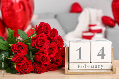 Fototapeta Naklejka Na Ścianę i Meble -  Calendar with date 14 FEBRUARY and roses on table in living room, closeup