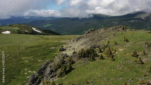 Aerial video of mount Sarlyk slopes. Drone flies along slope with snowfield and rocks. Altai highlands. photo