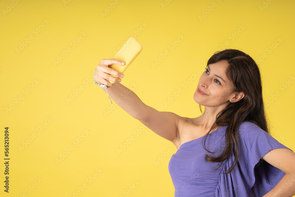Young lady posing cutely for a selfie with her yellow cell phone Young lady posing cutely for a selfie with her yellow cell phone