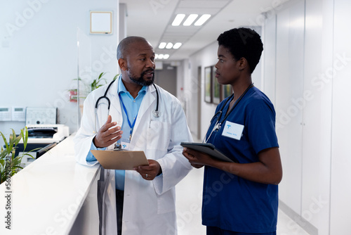African american male and female doctor talking in hospital corridor