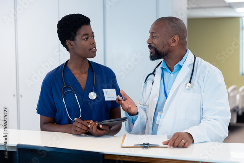African american male and female doctor talking in hospital corridor