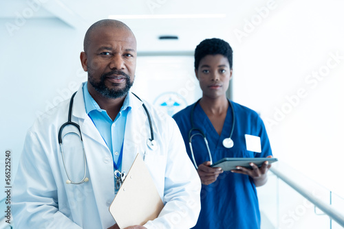 Portrait of serious african american male and female doctor in hospital corridor with copy space