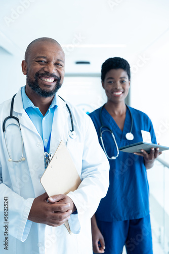 Portrait of happy african american male and female doctor in hospital corridor with copy space