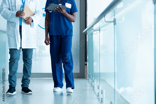 African american male and female doctor with tablet in hospital corridor with copy space