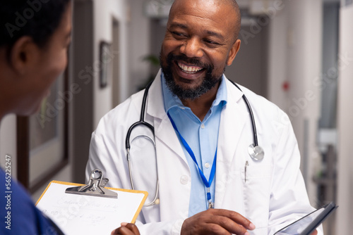 Smiling african american male and female doctor talking in hospital corridor