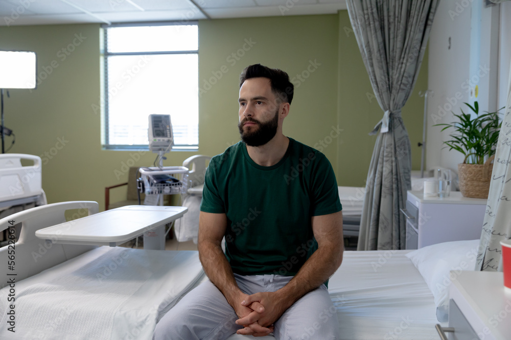 Caucasian male patient sitting on bed in room at hospital Caucasian male patient sitting on bed in room at hospital