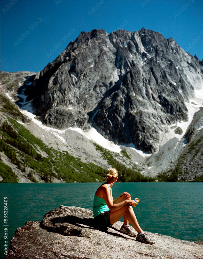 Colchuck Lake, Alpine Lakes Wilderness, Washington, USA. A young woman enjoys the turquoise waters of Colchuck Lake beneath Dragontail, a mountain in the Enchantments, Alpine Lakes Colchuck Lake, Alpine Lakes Wilderness, Washington, USA. A young woman enjoys the turquoise waters of Colchuck Lake beneath Dragontail, a mountain in the Enchantments, Alpine Lakes