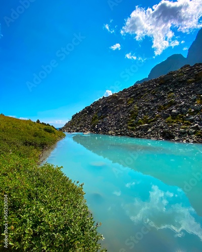 Turquoise mountain lake Karakabak against the background of peaks and stone rocks during the day in Altai in the summer. Vertical frame.
