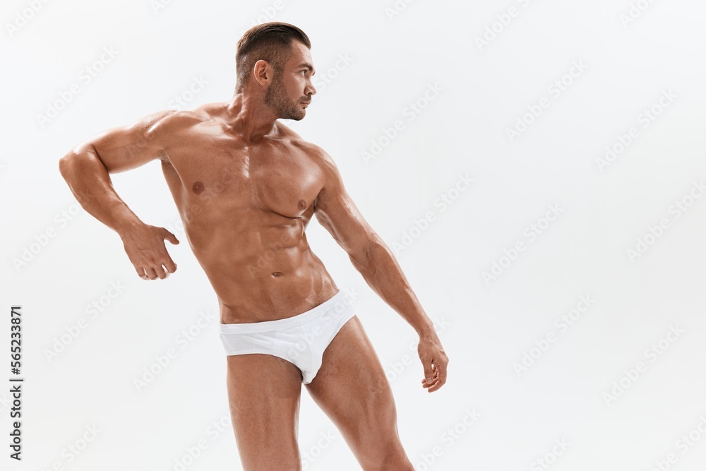 Man athletic body bodybuilder in briefs with naked torso abs full-length in the background, fitness classes. Advertising, sports, active lifestyle, competition, challenge concept.